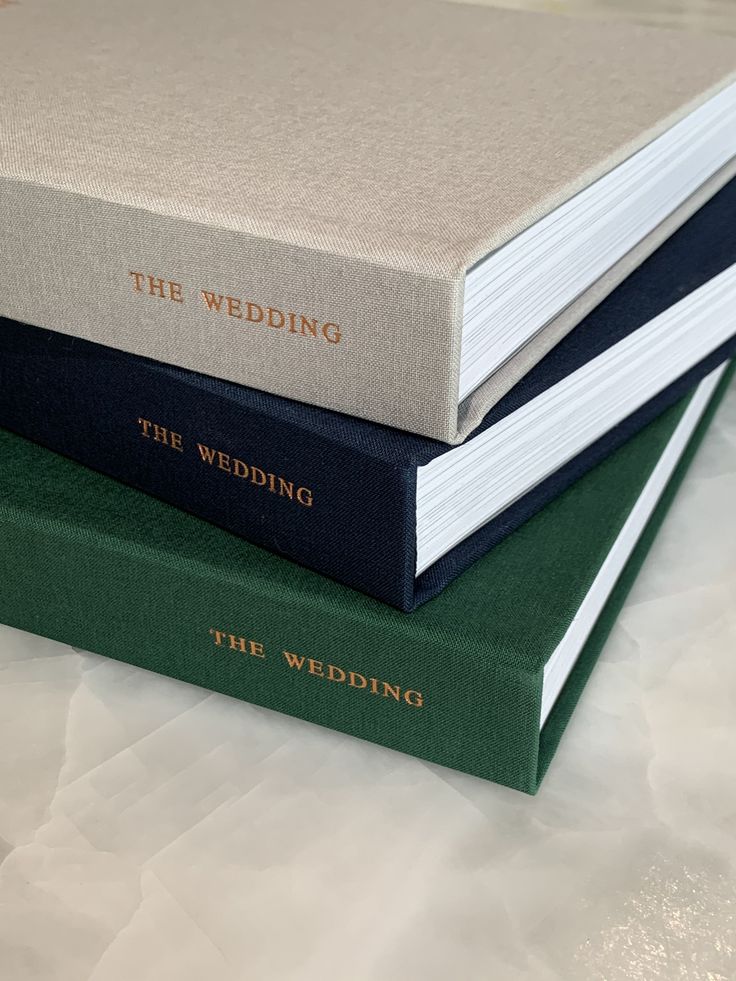 three books stacked on top of each other with the wedding written on one book in gold