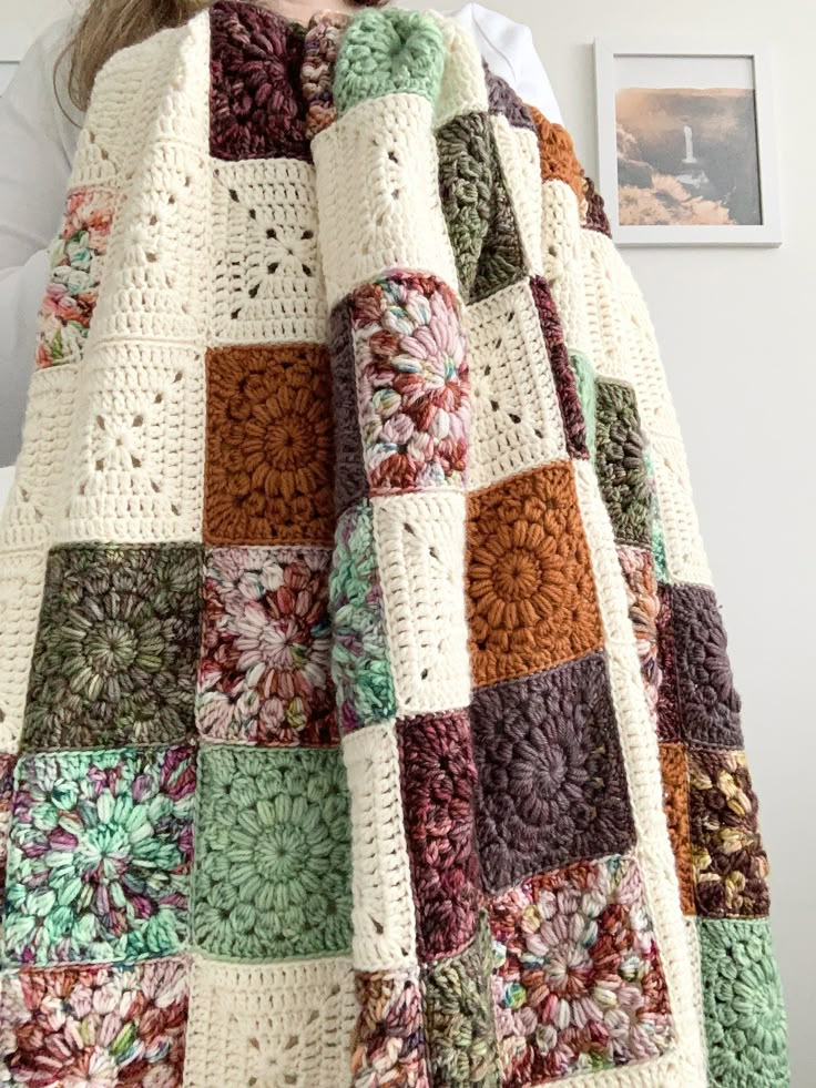 a woman wearing a crocheted blanket with flowers on it