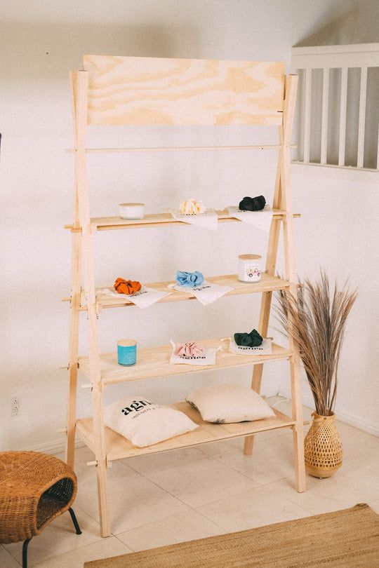 a wooden shelf sitting in the middle of a room next to a chair and rug