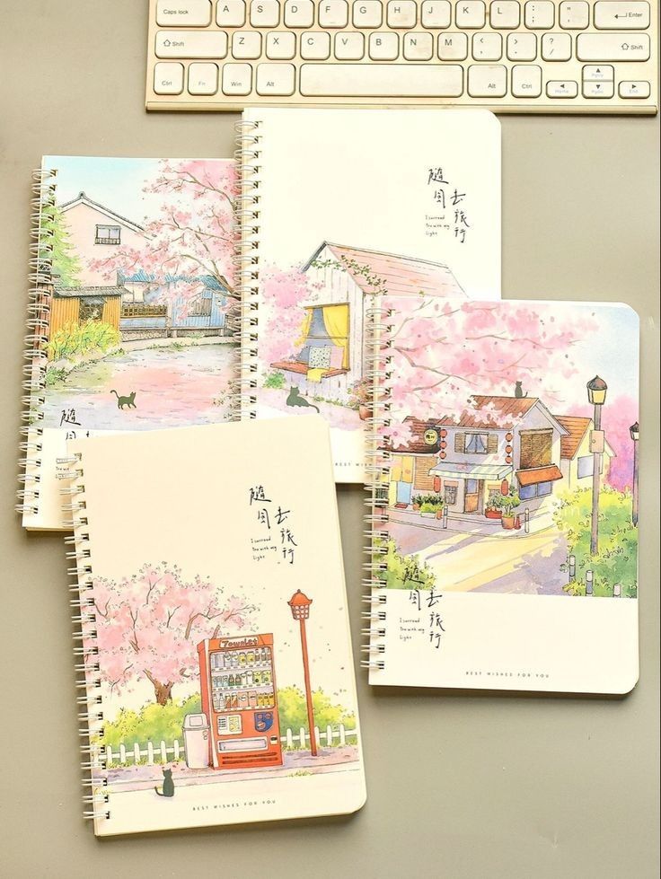 three notebooks with drawings on them next to a keyboard