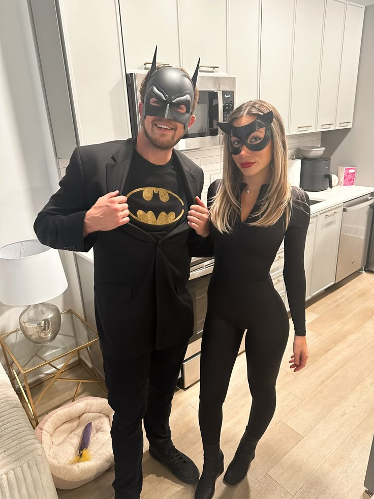 a man and woman dressed up as batman and catwoman pose for a photo in the kitchen