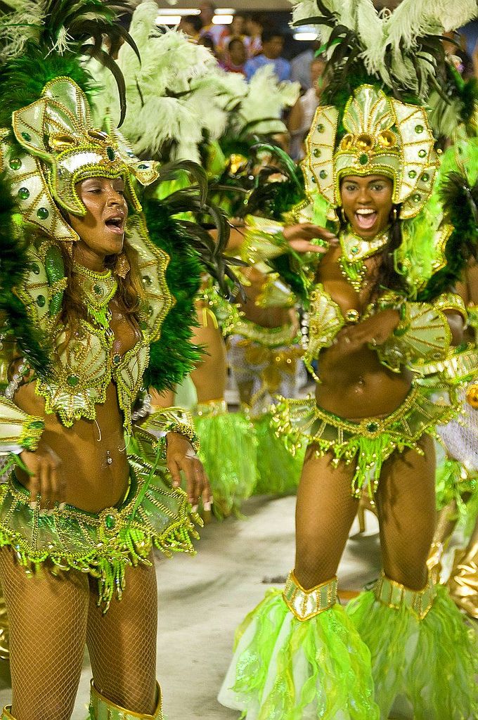 two women in green and gold costumes are walking down the street with their hands on their hips