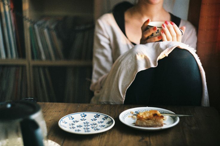 a woman sitting at a table with two plates and a cat in front of her