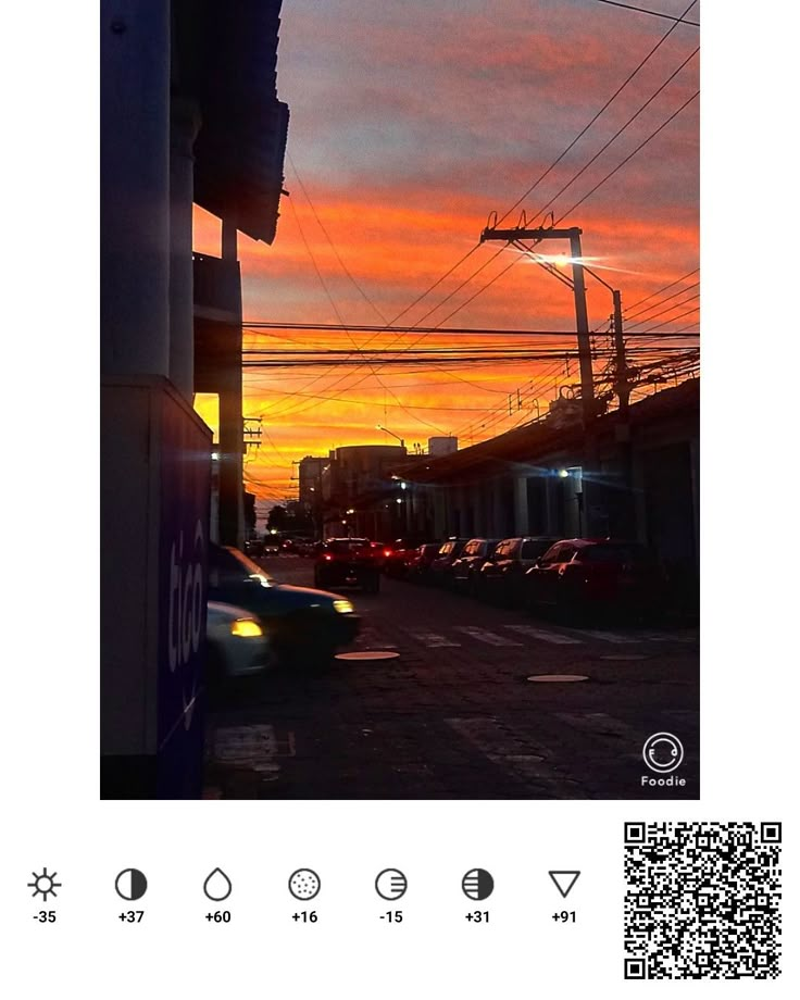 the sun is setting over a city street with cars parked on the side of the road