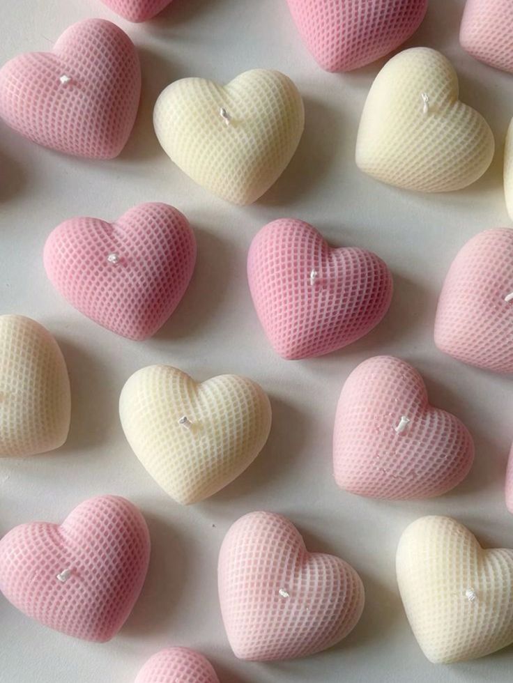 many pink and white heart shaped candies on a table