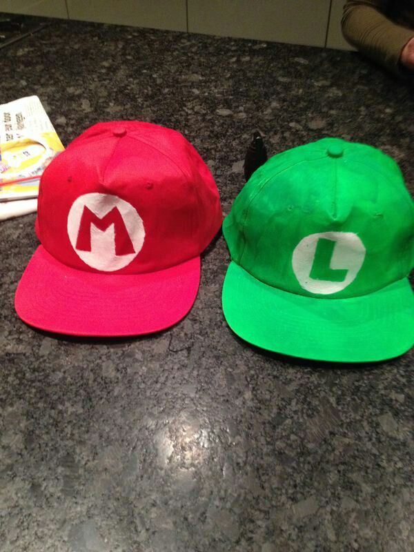 two hats sitting on top of a counter next to each other, one red and one green