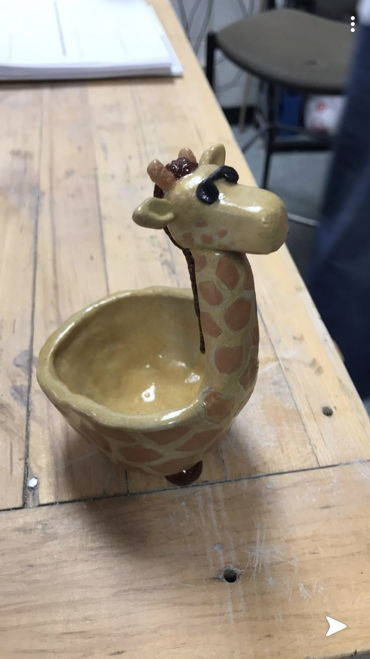 a giraffe shaped bowl sitting on top of a wooden table