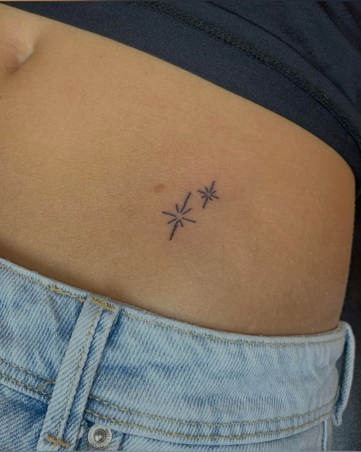 a woman's stomach with a small cross tattoo on it