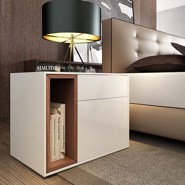 a nightstand with a lamp on top of it next to a bed