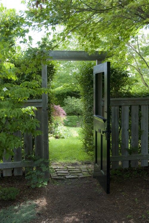 an open gate leading into a lush green yard