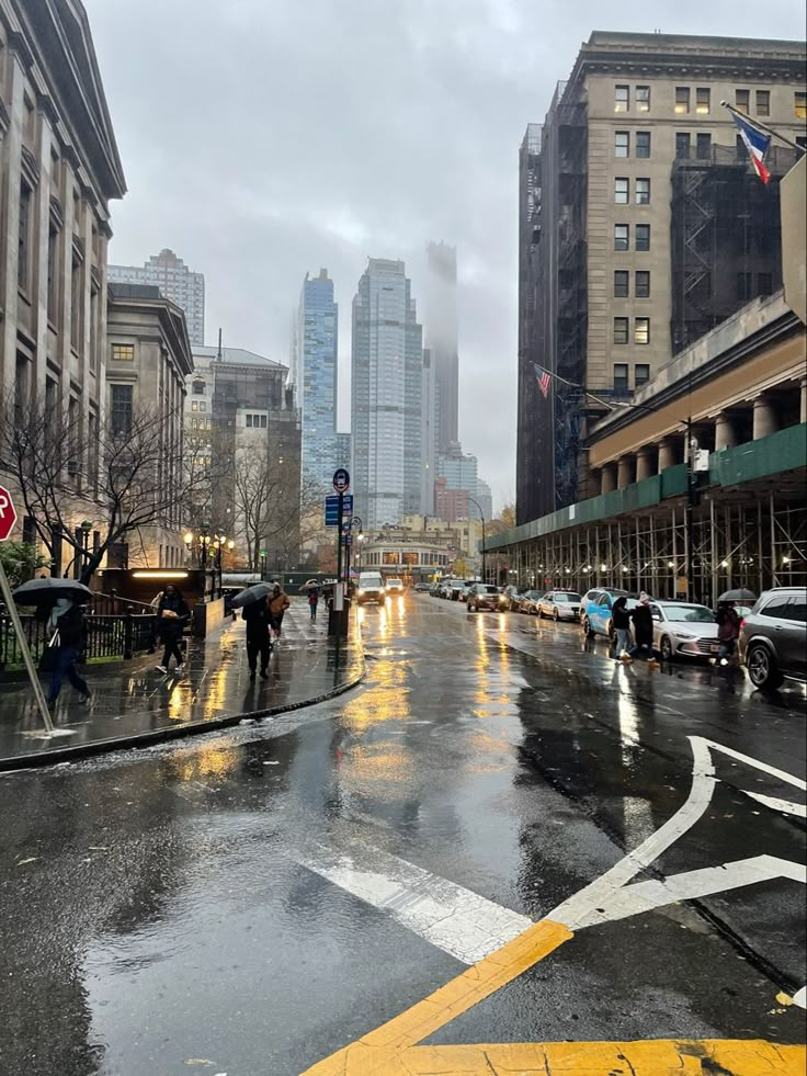 people crossing the street on a rainy day with buildings in the background