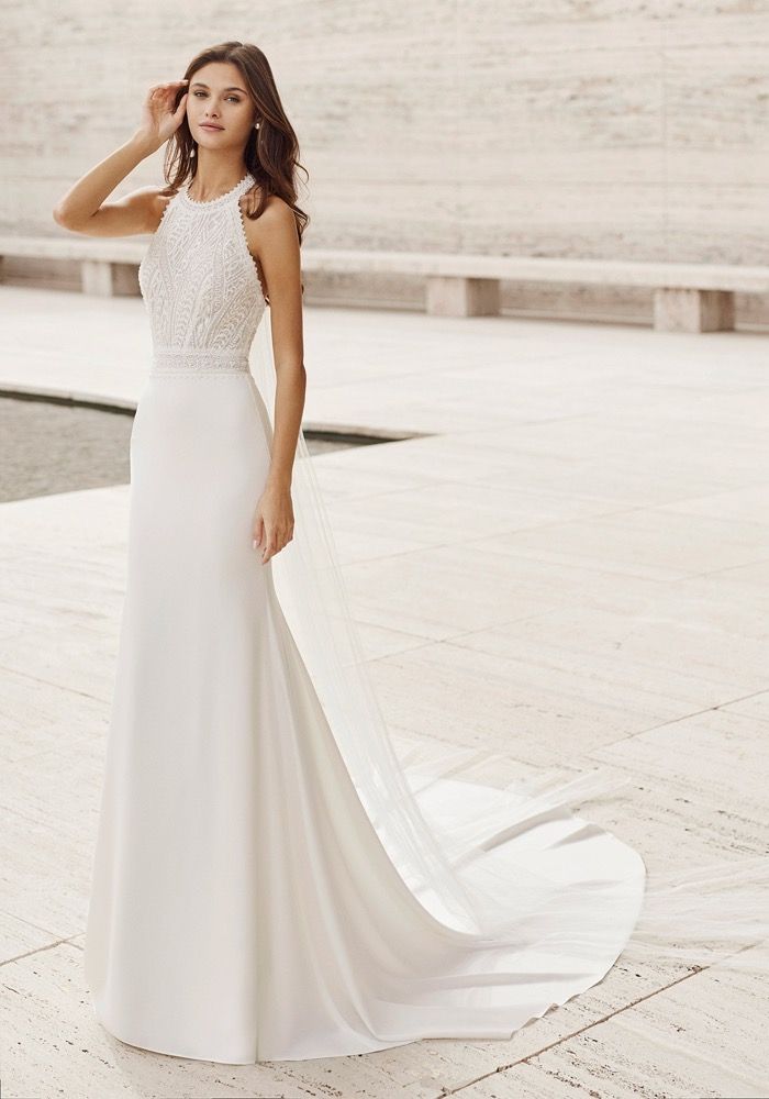 a woman in a white wedding dress standing on a stone walkway next to a body of water