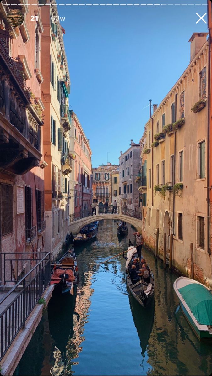 several boats are parked along the side of a narrow canal in venice, italy on a sunny day