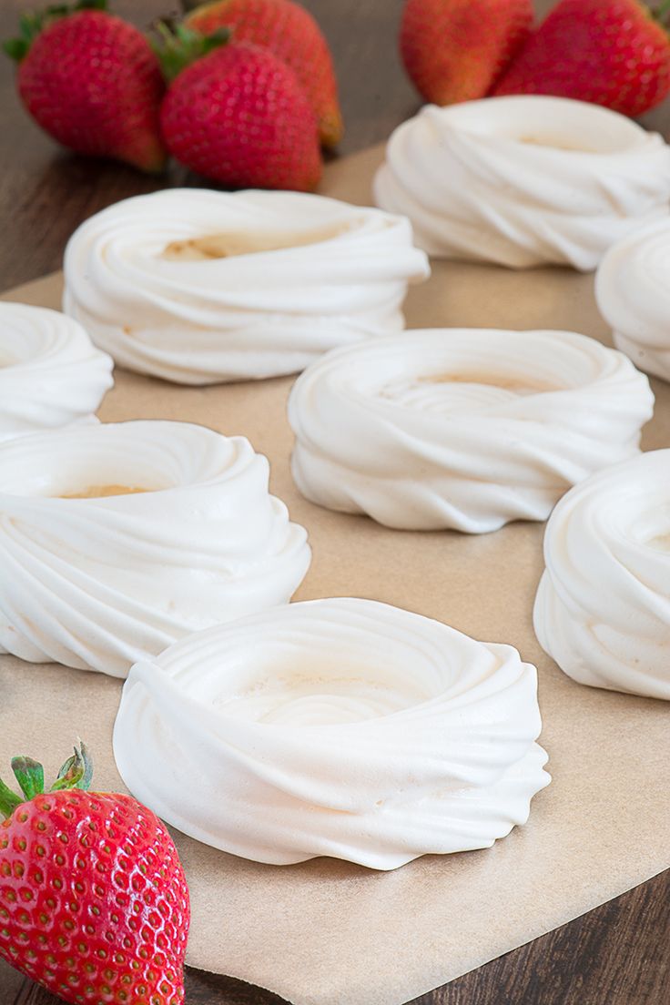 strawberries and whipped cream are arranged on a piece of brown parchment paper with white icing