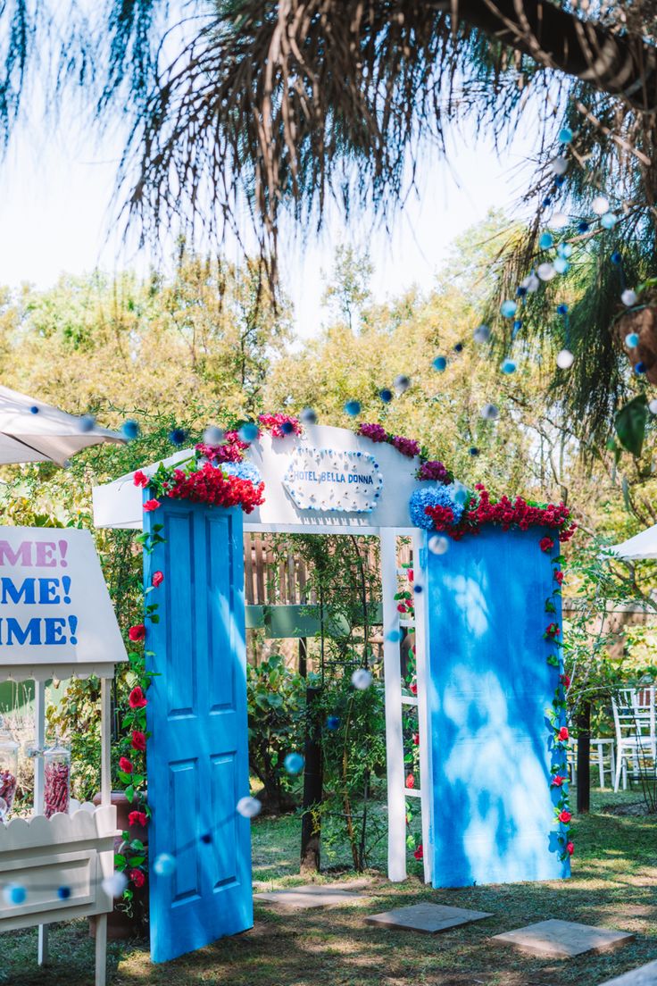 a blue and white door is in the middle of a yard with flowers on it