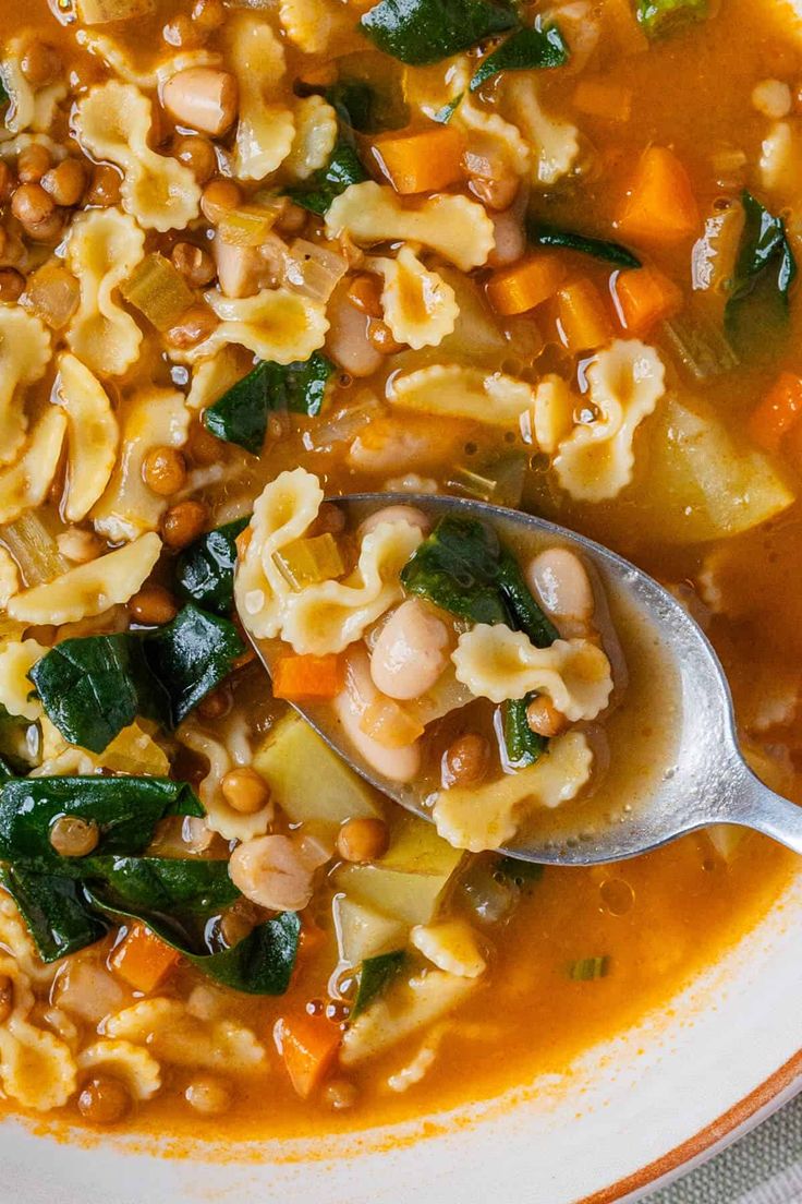 a white bowl filled with pasta and spinach soup