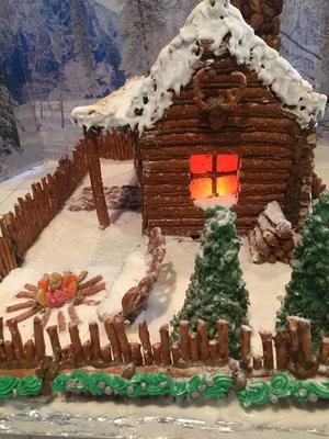 a gingerbread house is decorated with icing and frosting on the outside, along with pine trees