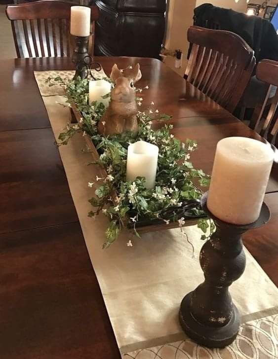 a dining room table with candles and flowers on the centerpiece, surrounded by greenery