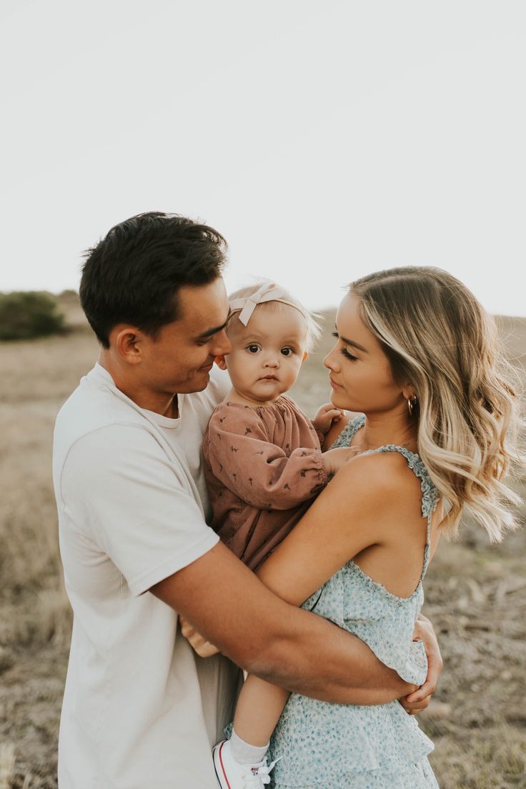 a man and woman holding a baby in their arms