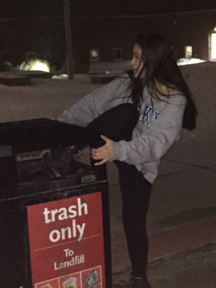 a woman standing next to a trash can