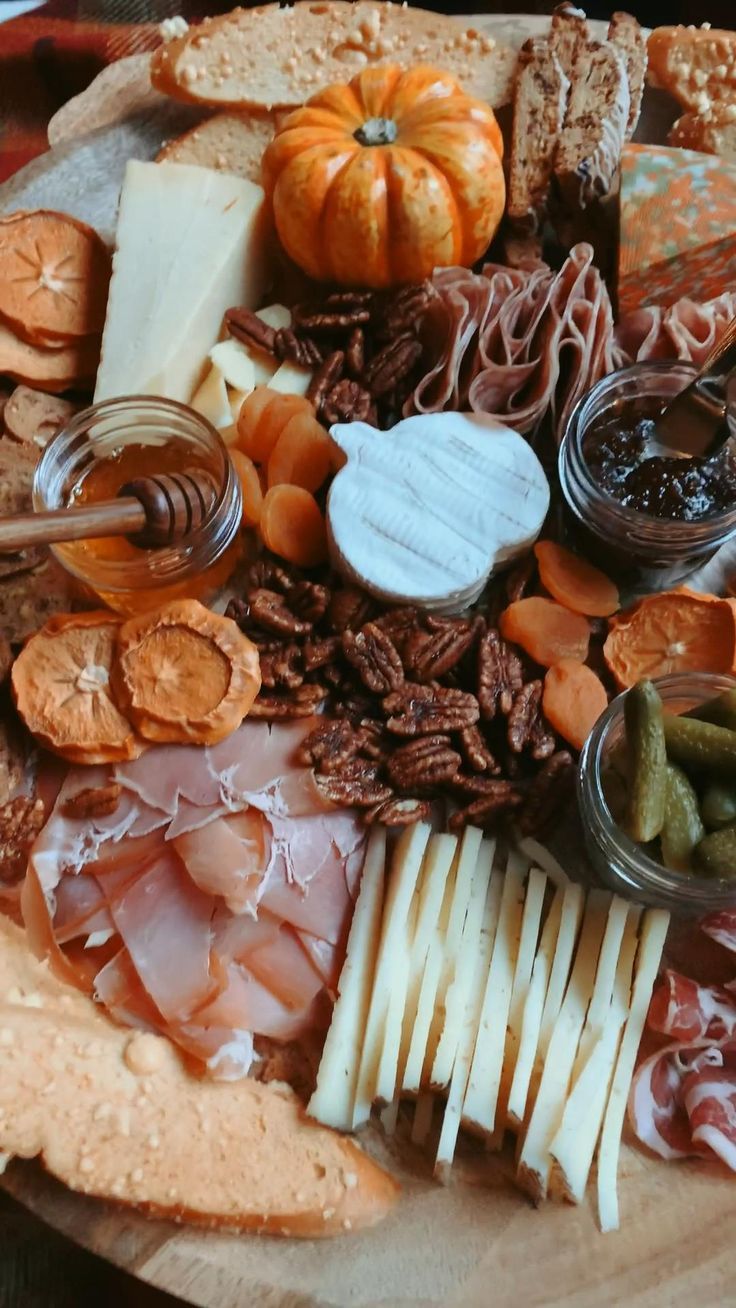 an assortment of cheeses, meats and vegetables on a platter with crackers