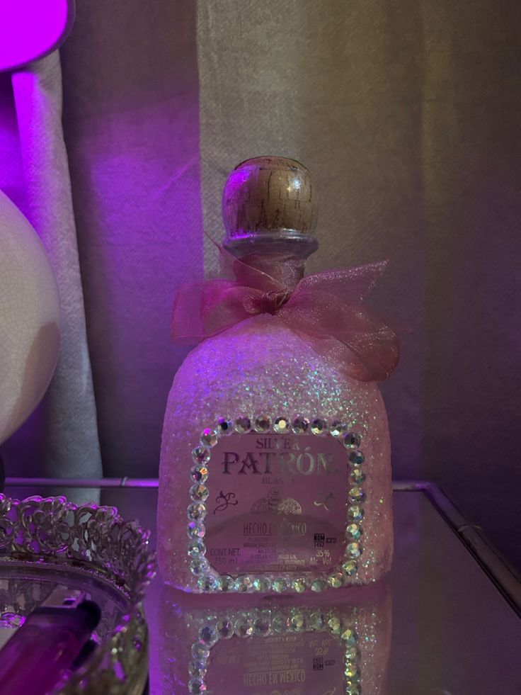 a bottle of pink liquid sitting on top of a glass table next to a mirror