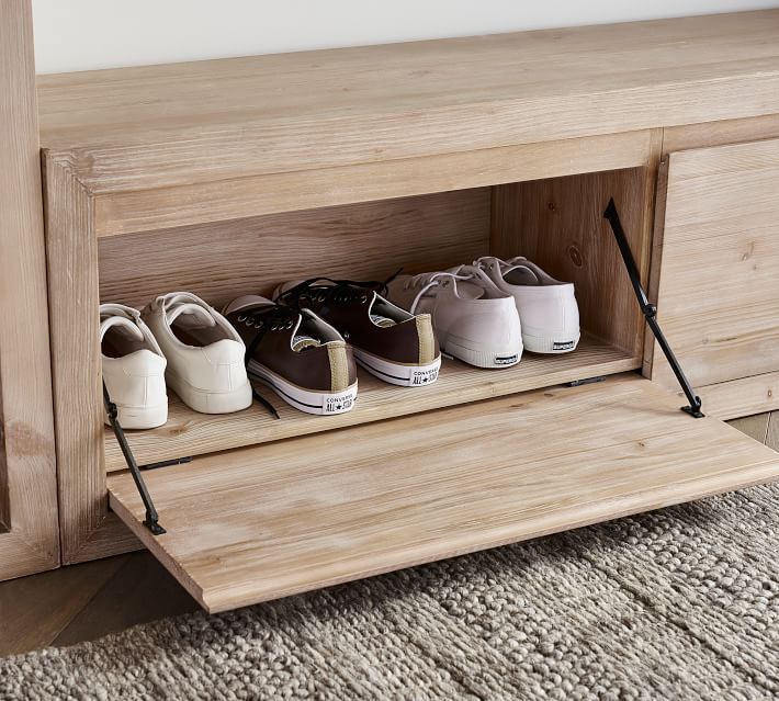 three pairs of shoes are sitting on a shelf in front of a bed and rug