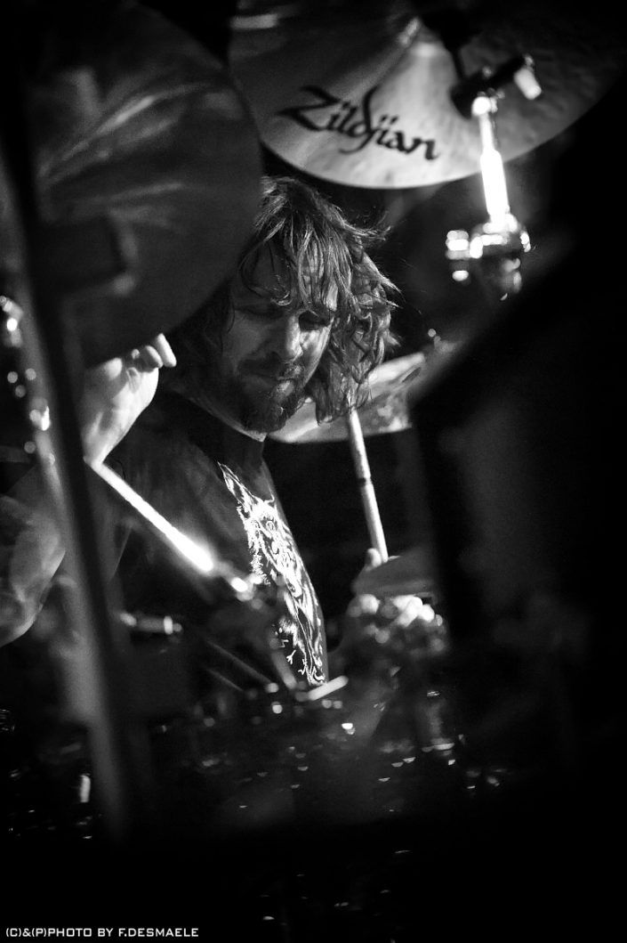 a man with long hair playing drums