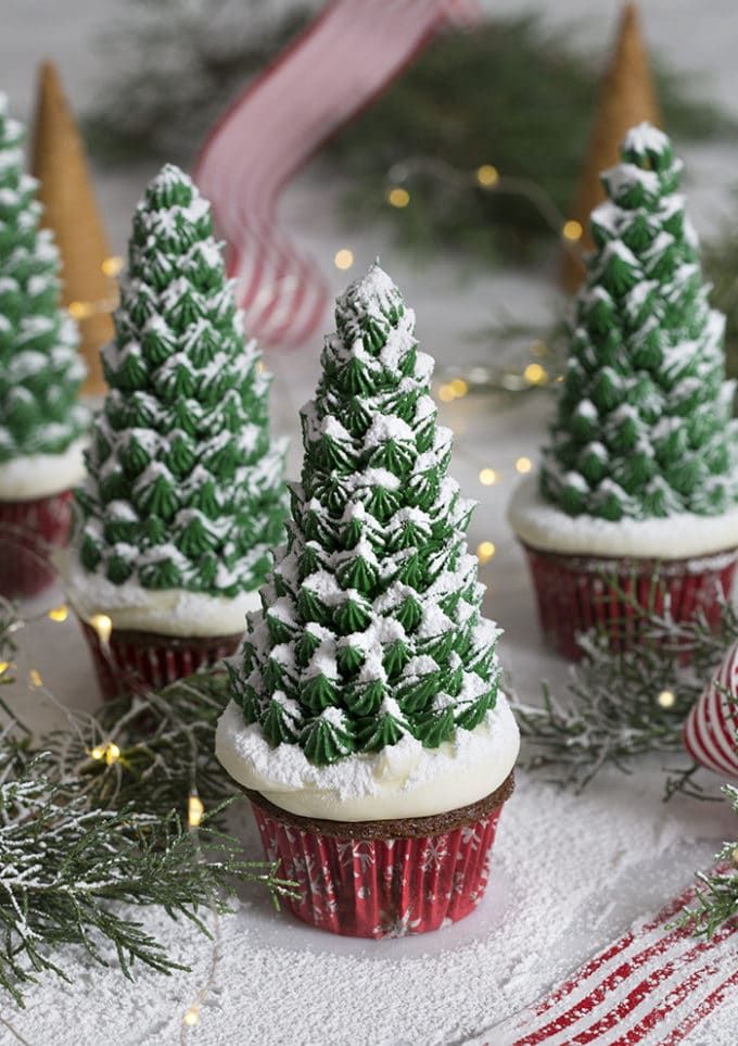 cupcakes decorated with frosting and christmas trees on top of snow covered ground