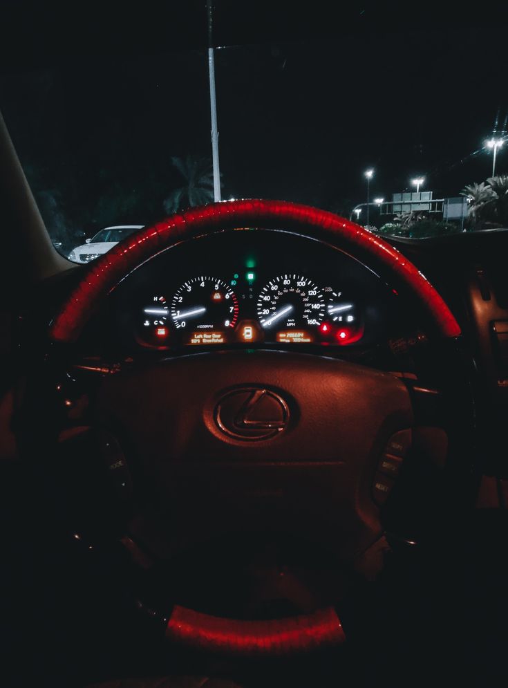 the dashboard of a car at night with its lights on and steering wheel illuminated up