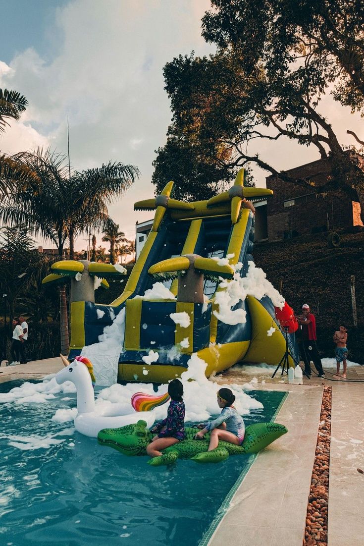 two children playing in an inflatable water slide at the edge of a swimming pool