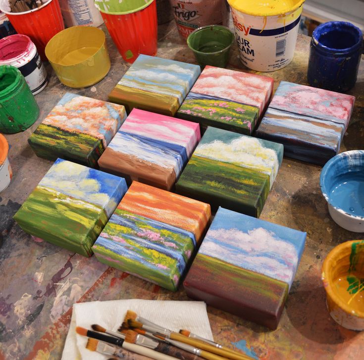 many different colored paintings on a table with paintbrushes