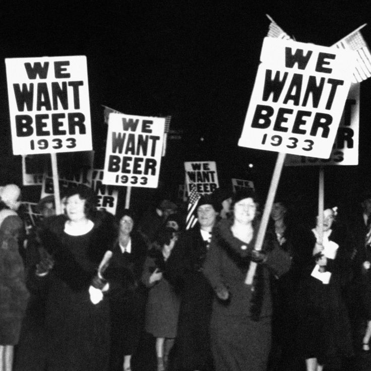 several women holding signs and standing in front of a crowd at night with american flags