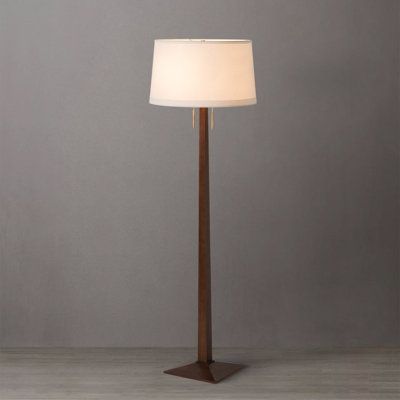 a floor lamp with a white shade on it's side and a wooden base