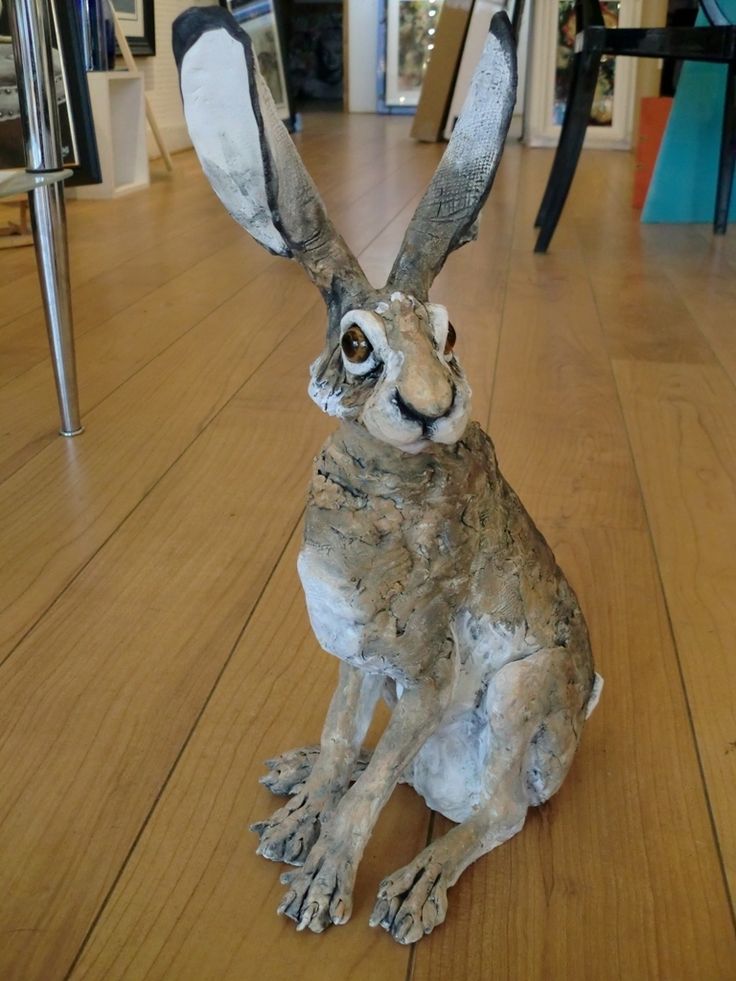 a statue of a rabbit sitting on top of a wooden floor