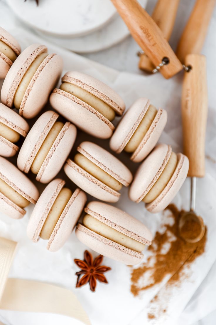 several macaroons are arranged on a table with cinnamon sticks and anisette