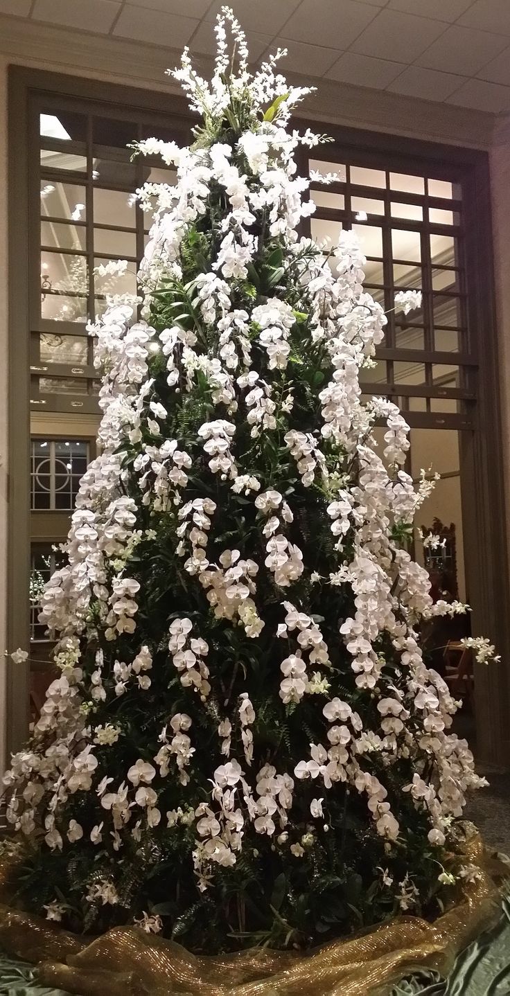 a christmas tree with white flowers in an office building