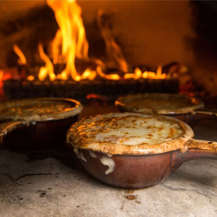 three pot pies sitting in front of an open fire place with flames behind them