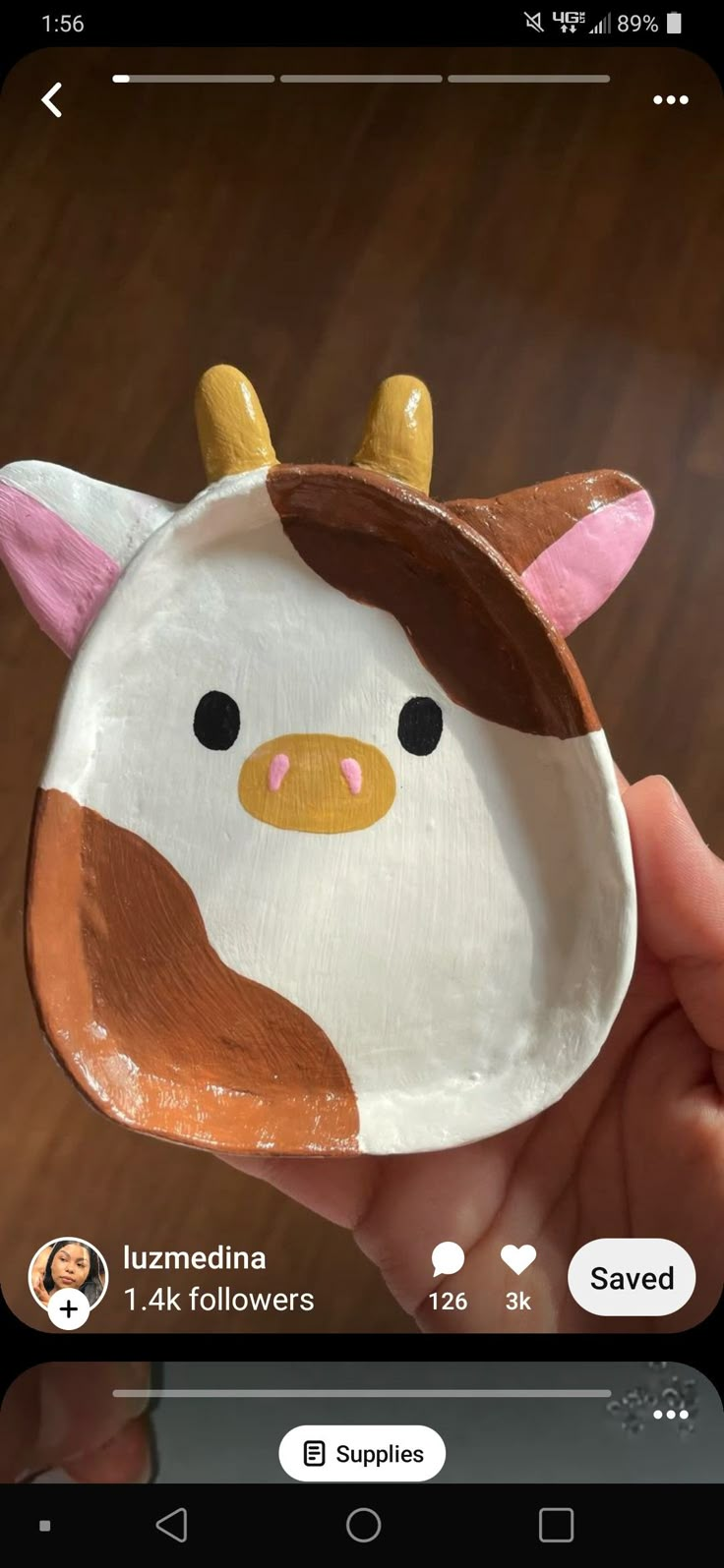 a hand holding a paper plate with a cow on it's face and horns