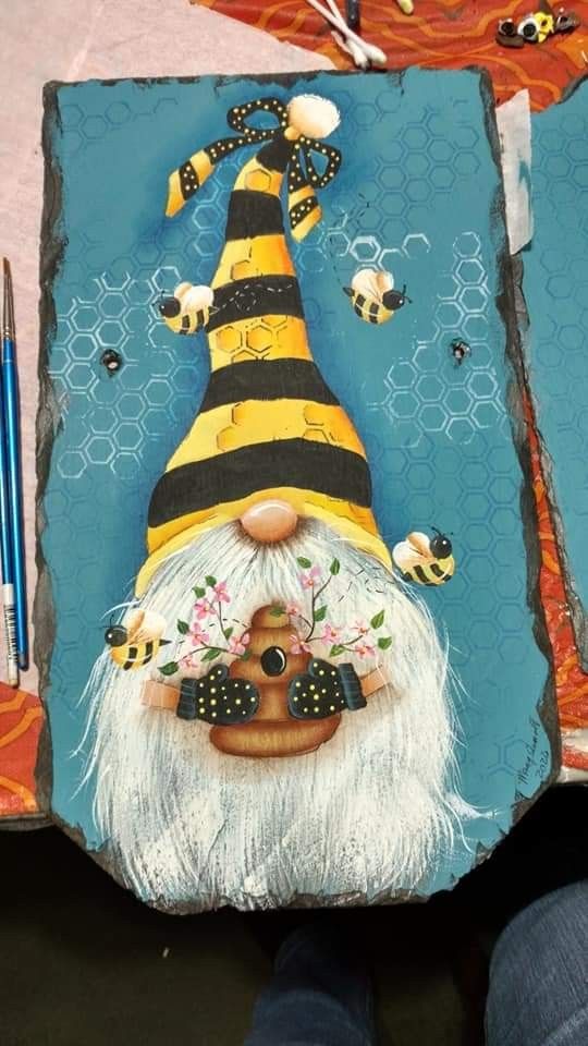 a painting of a gnome with bees on it's face and some pencils next to it