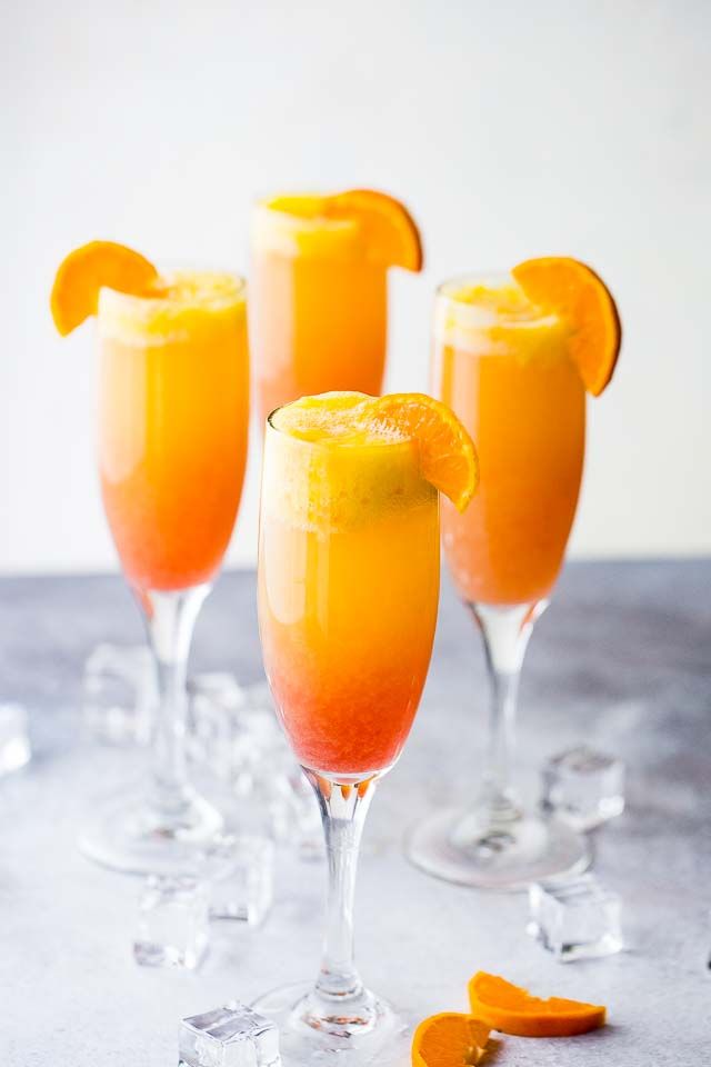 three glasses filled with orange juice and garnished with an orange slice on the rim