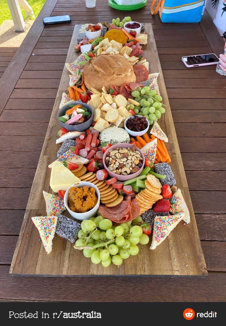 a long wooden table topped with lots of different types of food and snacks on top of it