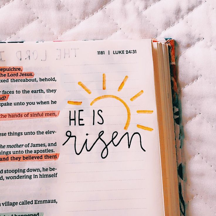 an open bible with the words he is risen written in cursive writing on it