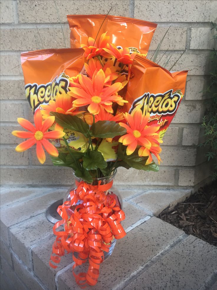 a vase filled with orange flowers sitting on top of a cement block next to a brick wall