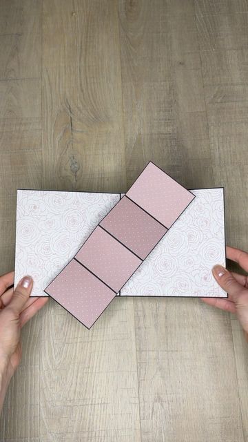 two hands holding an origami piece on top of a wooden table