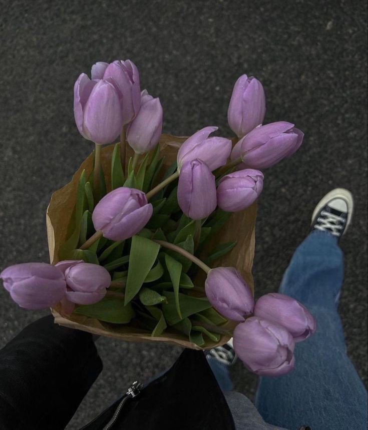 a bouquet of purple tulips in someone's hand