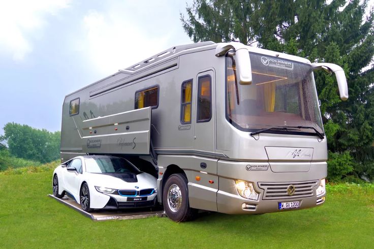 an rv parked next to a car in the grass