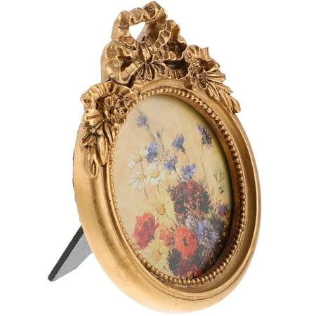 an ornate gold frame with flowers on it and a knife sticking out of the side