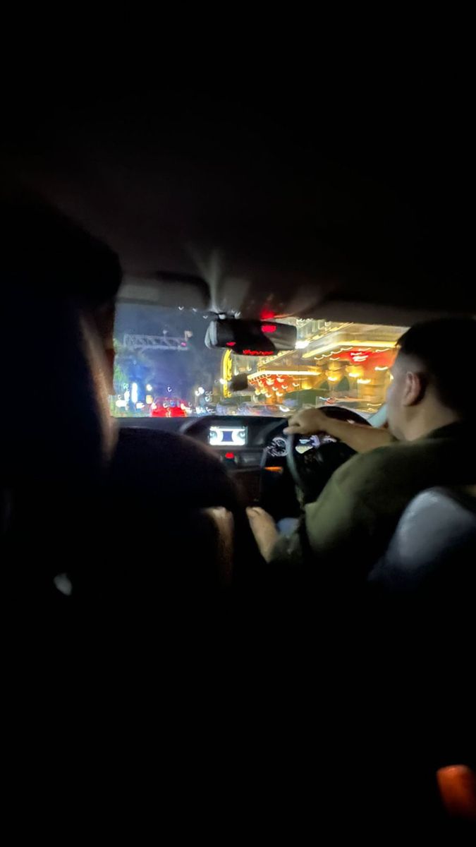 two people sitting in the passenger seat of a car at night