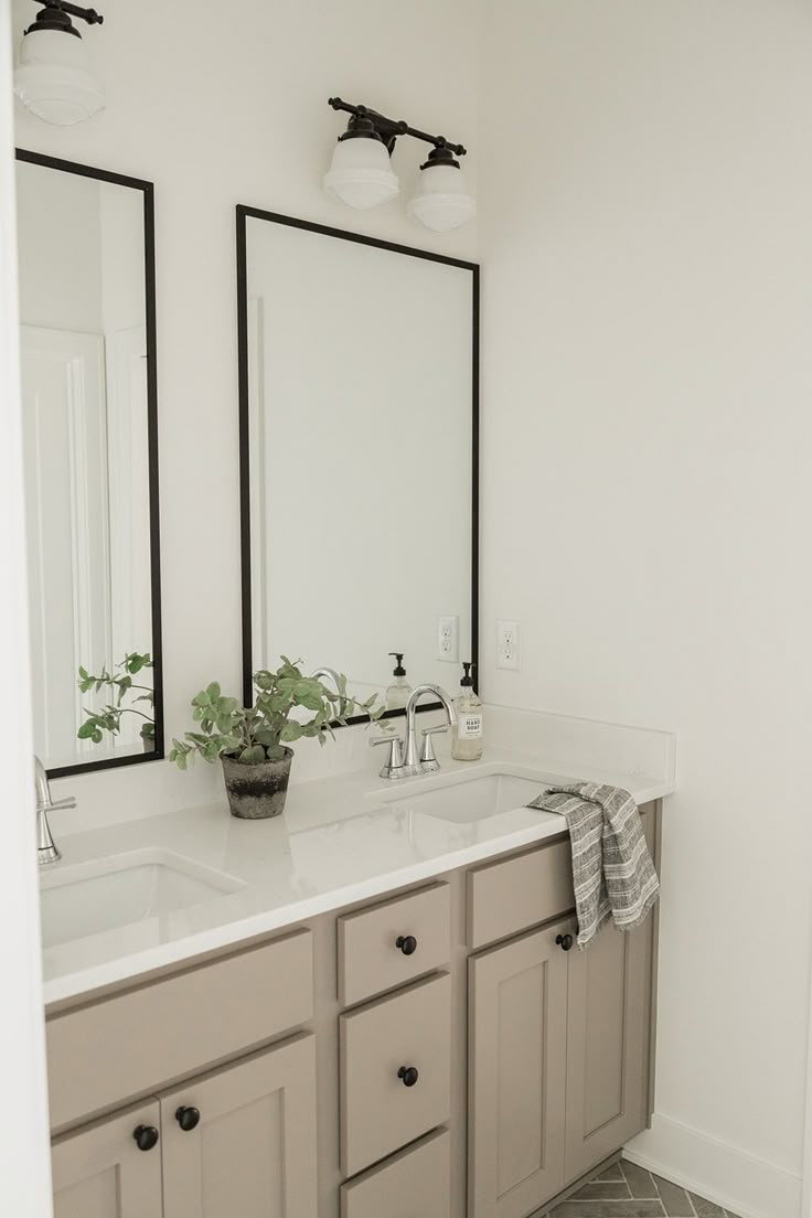 a bathroom with double sinks and two mirrors